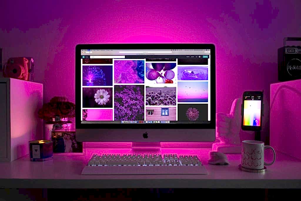 Modern desk setup with neon lighting and a desktop computer displaying colorful images. ankara en iyi web tasarim ajansi