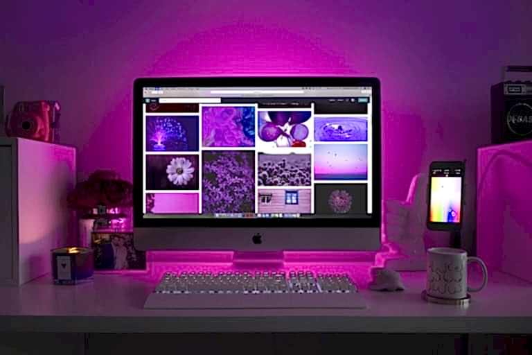Modern desk setup with neon lighting and a desktop computer displaying colorful images. ankara en iyi web tasarim ajansi