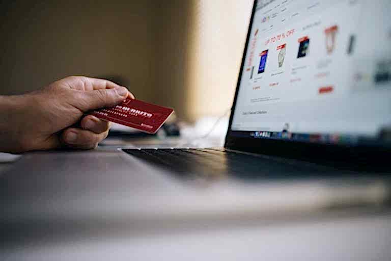 Person holding a credit card while shopping online on a laptop, indicating ecommerce transactions. ankara e-ticaret web sitesi yapimi ve paketleri