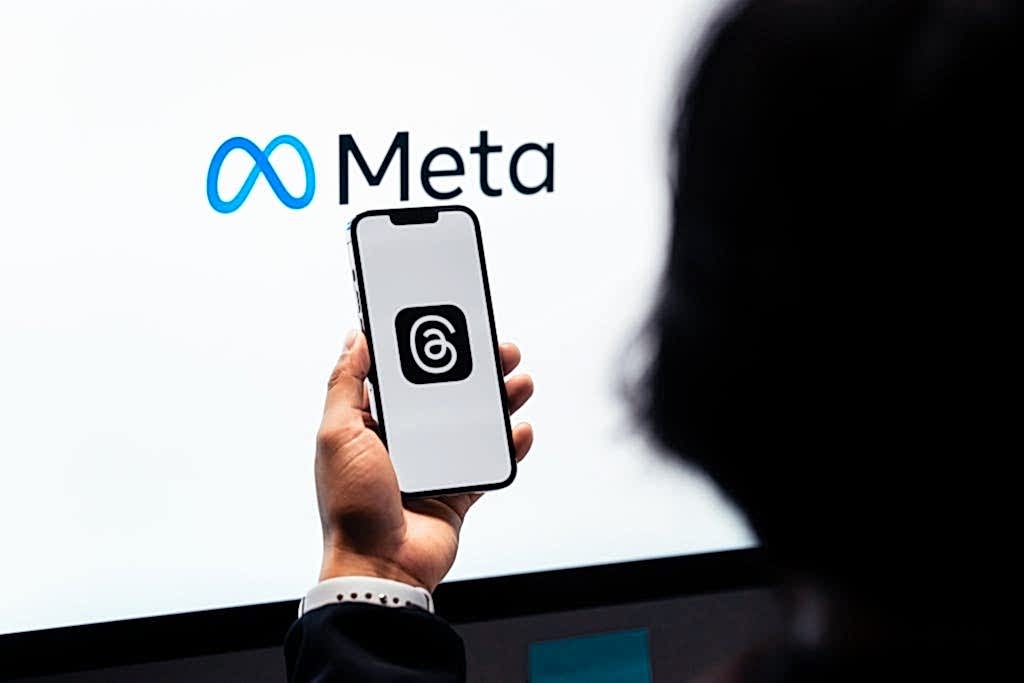 Hands holding smartphone with Meta Threads logo on screen, Meta branding in background. Meta Reklam Hesabı Neden Kapanır?
