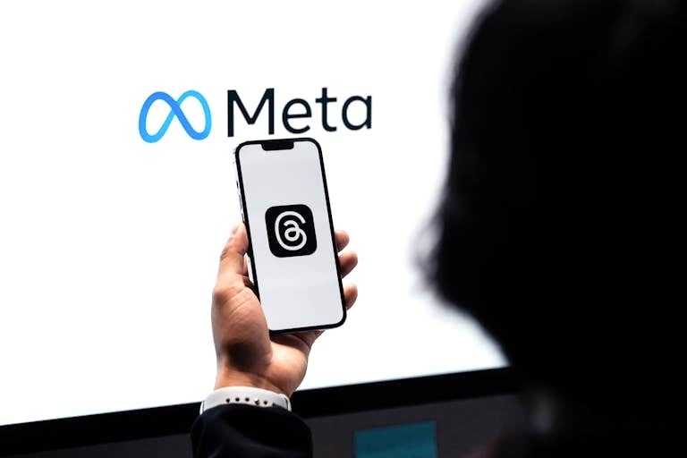 Hands holding smartphone with Meta Threads logo on screen, Meta branding in background. Meta Reklam Hesabı Neden Kapanır?